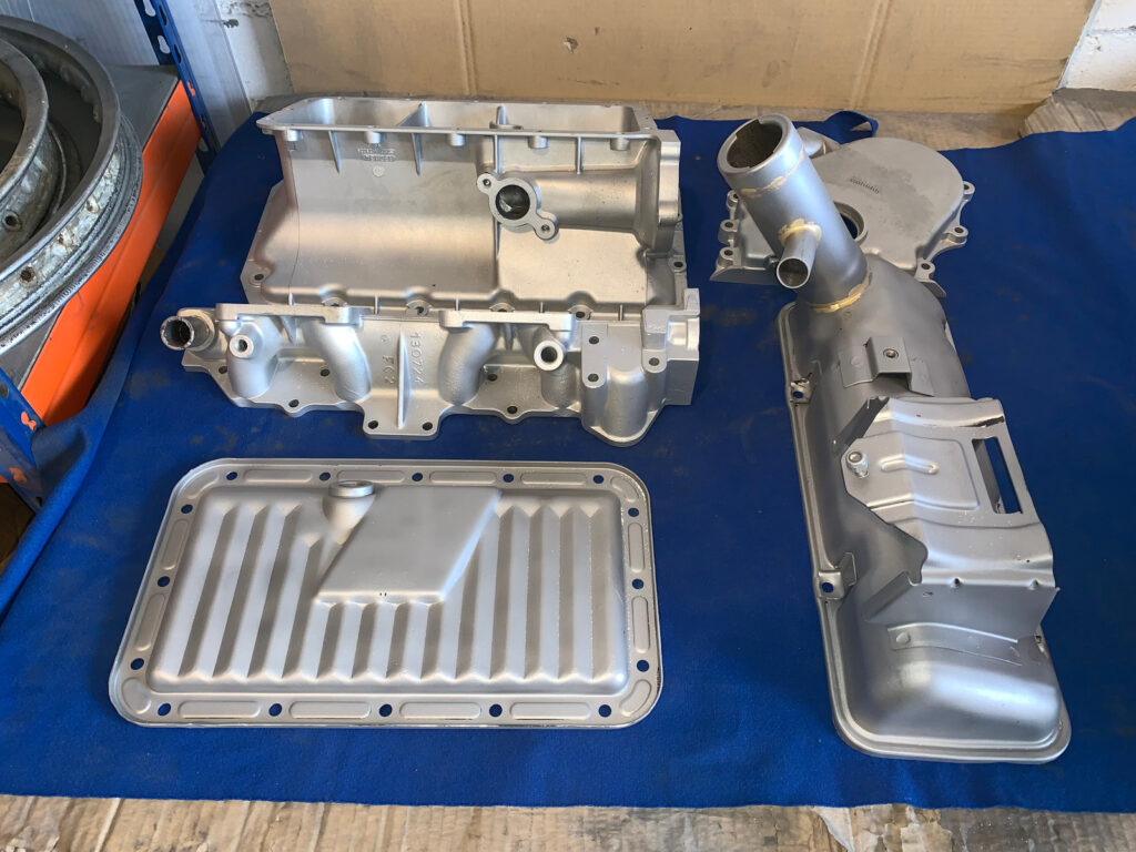 Las mismas piezas de motor tras el chorreado, con un gris mate uniforme